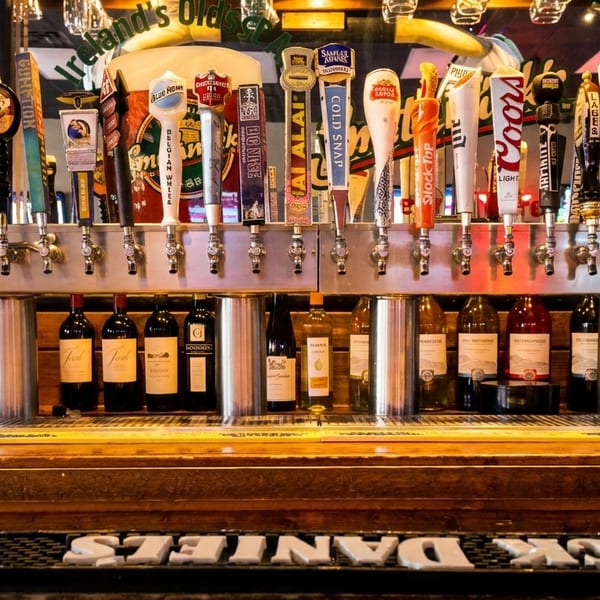 A bar with many beer taps, bottles of wine, and liquor on wooden shelves.