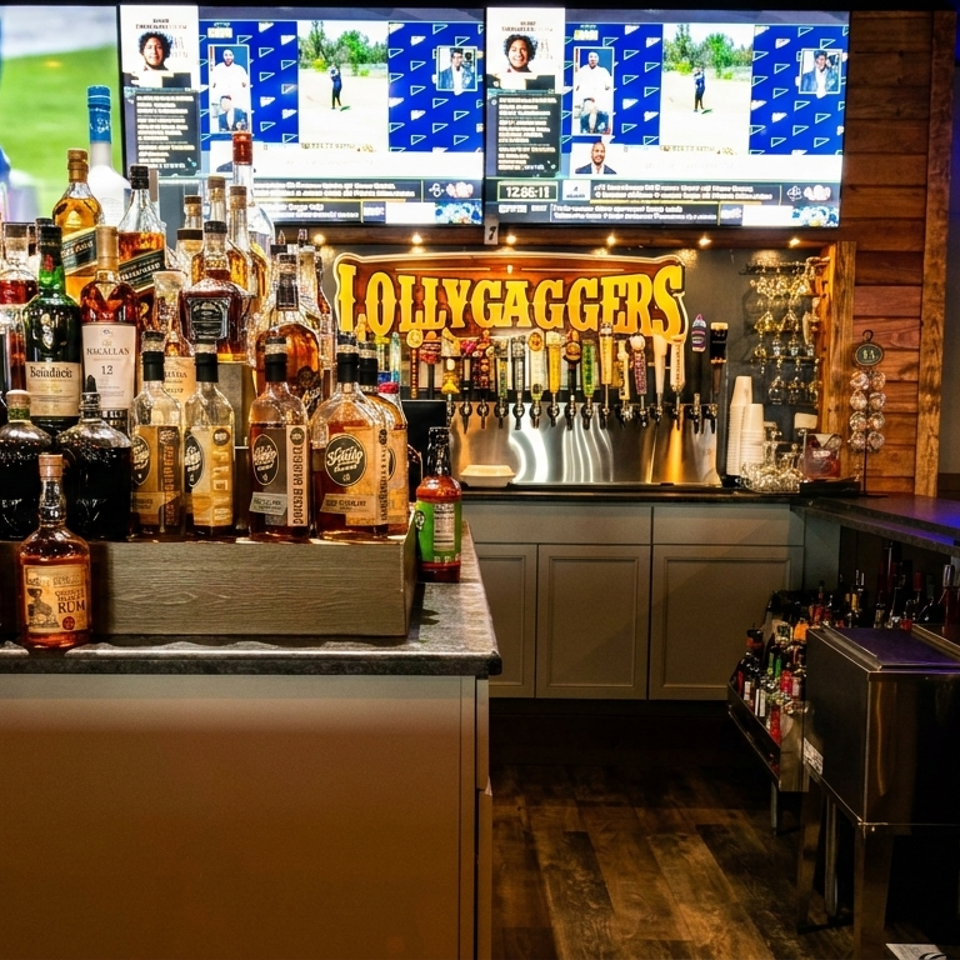 A well-stocked bar at Lollygaggers with liquor bottles, beer taps, and sports on multiple TVs.